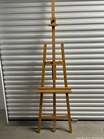 Large wood easel front view showing adjustable central support and canvas shelf.