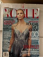 Cover of Vogue magazine featuring Charlize Theron wearing a silver dress, containing articles on holiday gift guide and other lifestyle topics.