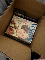 Top-down view of cardboard box filled with Vogue magazines and DVDs