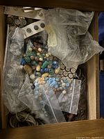 Top view of the case drawer filled with assorted buttons, snaps, hooks, and other small sewing supplies packed in plastic bags.