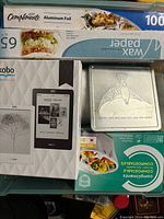 Photo showing Kobo Touch Edition e-reader box alongside kitchen wrap supplies and metal storage box
