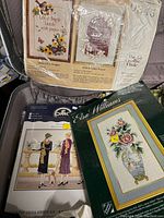 Close-up of several embroidery kits in packaging showing floral and figurative patterns with packaging details.