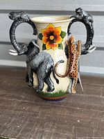 Front view showing elephant, leopard, and floral design with elephant trunk handle