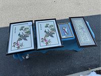 Overview of all four framed embroidered panels displayed on a table outside