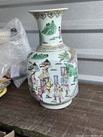 Front and side view of porcelain vase showing battle scene with figures on horseback, umbrellas, green hills and palace windows.