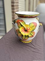 Front and side view of the ceramic vase showing the colorful 3D flowers and animal figures.