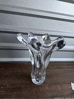 Front angled view of clear crystal splash vase showing ribbon-like flared rim and thick glass