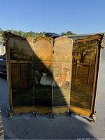 Front view of the entire four-panel hand-painted dressing screen outside in sunlight showing the detailed painting and carved wood frame.