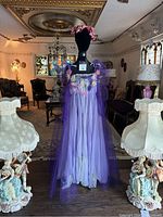 Purple chiffon and tulle nightgown displayed on a black mannequin with a floral crown in an ornate living room. The nightgown features handmade tulle flowers in multiple colors on the bust area and shoulder accents.