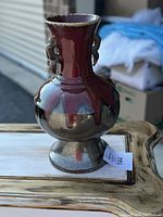 Front and side view of antique vase showing oxblood flambe glaze and sculpted handles.