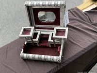 Open vintage metal embossed jewelry box showing interior compartments and mirror