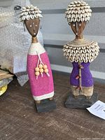 Pair of Namji fertility dolls with detailed beadwork, cowrie shell adornments, and wooden bases.