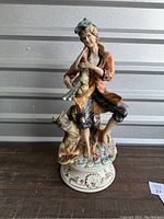 Full view of porcelain Capodimonte figure sculpture of boy with dog, showing colorful painted details and ornate base.