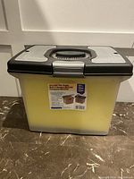 Closed portable file caddy showing yellow semi-transparent body and black lid with handle and label.