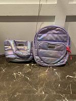 Photo showing two purple sparkly Justice bags, one handbag and one backpack.