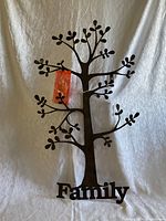 Photo of metal family tree wall decor hanging against a white textured backdrop.