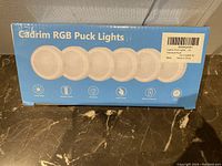 Box front showing 'Cadrim RGB Puck Lights' text and six puck lights illustration with feature icons