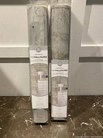 Two rolls of Wall Pops NuWallpaper peel and stick wallpaper against a white door, showing packaging and design.