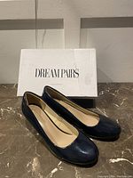 Photo of navy blue Dream Pairs heels with original box behind the shoes.