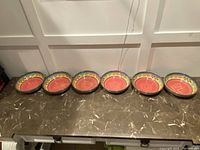 Seven round melamine bowls lined up on a countertop showing their design and quantity.