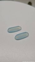 Pair of natural aqua blue chalcedony gemstones, pill cut shape, smooth polished finish shown on white background.