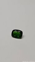 Front angle photo showing the deep green cushion cut chrome diopside gemstone with faceted surface and reflective shine.