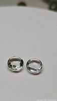 Two small round, button cabochon-style green amethyst gemstones with checkerboard faceted tops on white background