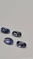Four oval cut natural tanzanite gemstones showing color and clarity characteristics.