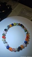 Clear top-down image of the bracelet showing mixed colored beads on a white circular background with some shadows.