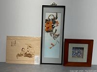 Front view of three framed wall art pieces showing detailed features and layout of the lot.