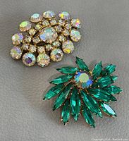 Top view of two vintage 1960s rhinestone brooches on grey background.