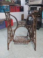 View of the front side of the antique cast iron Pfaff sewing machine stand showing the treadle pedal and 'PFAFF' name.