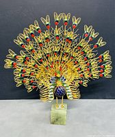 Front view of the Chinese cloisonné peacock figure showing full tail spread and stone base.