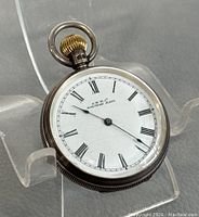 Front view of sterling silver pocket watch showing white dial with Roman numerals and A.W.W.Co marking