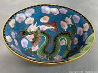 Top and inside view of the bowl showing detailed cloisonné dragon and cloud design with vibrant colors on blue background and gold rim.