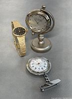 Overview photo showing the Hamilton wristwatch, Classic desk clock, and silver-tone pocket watch together on gray surface