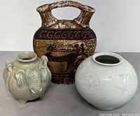Photo showing front view of three ceramic vases: brown handled decanter with ancient boat design in the center, light green elephant vase on left, white round vase on right