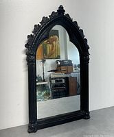 Frontal image of the black painted tall arch wall mirror showing detailed carved frame and clear reflective glass.