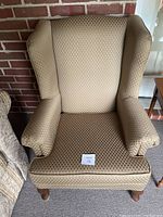 Three-quarter view of light brown diamond-patterned upholstered wingback armchair showing overall shape
