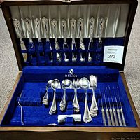 Full view of the Birks Regency flatware set arranged in the original blue velvet-lined wooden chest showcasing 43 pieces including forks, spoons, and knives with detailed embossed Cascade pattern handles.