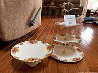 Both dessert stand and cake stand visible on wood floor showing floral pattern and gold detailing.