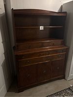 Full view of wooden hutch showing open shelves on top, drawers in the middle, and cabinet doors below.