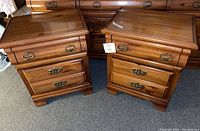Front view of two wooden nightstands showing grain details and brass drawer handles.