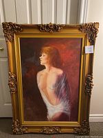 Full view of the framed painting showing the ornate gold frame and the woman in white drapery.