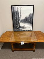 Full view of coffee table with painting leaning on top, showing the wooden finish and extension wings