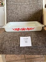 Front view of the rectangular white Pyrex baking dish with red bird and flower design on the side.