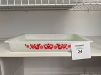 Side view of the white opaque glass rectangular Pyrex dish showing the red Friendship bird and floral pattern in the center of the long side