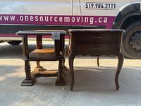 Pair of wooden side tables shown together, one with two drawers and curved legs, the other with glass top and shelving beneath.