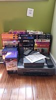 Lot showing Sanyo VCR player, Digitec DVD/CD player, and VCR tape collection arranged on floor