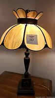 Vintage 8-panel caramel amber stained glass table lamp illuminated showing bronze tone metal base.